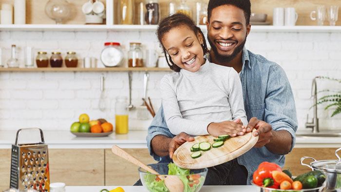 dad and daughter preparing vegetable salad dinner